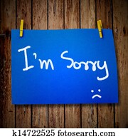 note paper and clothes peg on a wooden background with sorry message