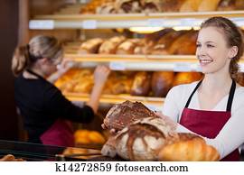 saleswoman in bakery in front of shelves saleswoman in bakery in front of shelves