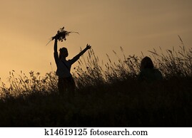 Silhouettes of girl picking flowers during midsummer soltice 