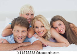 Smiling family lying on bed