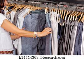 Woman Choosing Trouser From Rack In Clothing Store