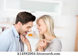 Woman Feeding Food To Man In Kitchen
