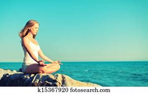 woman meditating in  lotus yoga on beach