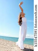 Woman relaxing at the beach with arms open enjoying her freedom