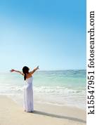 Woman relaxing at the beach with arms open enjoying her freedom
