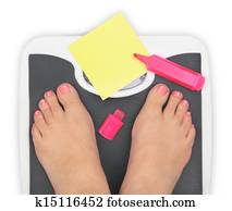 Woman' s feet on bathroom scale and blank notepaper