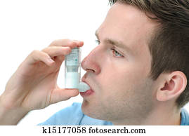 Young man using an asthma inhaler