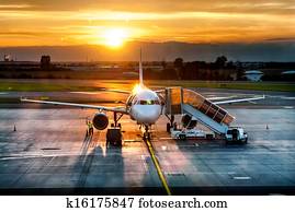 Airplane near the terminal in an airport at the sunset Airplane near the terminal in an airport at the sunset