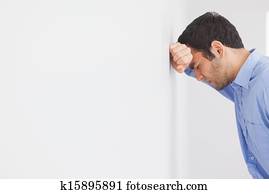 Angry man leaning his head against a wall