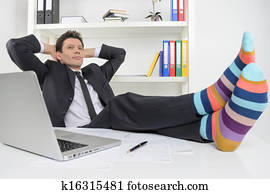 Businessman in funky socks. Confident businessman holding his legs in funny socks on the desk