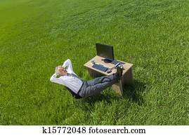 Businessman Relaxing Thinking At Desk in Green Field