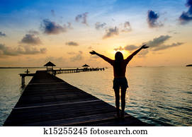 Carefree woman in the sunset on the pier. vacation vitality healthy living concept