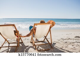 Cute couple lying on their deck chairs