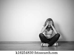 girl sits in a depression on the floor near the wall