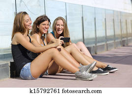 Group of three teenager girls laughing while watching the smart phone