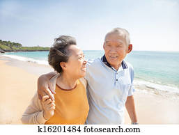 happy asian seniors walking on the beach