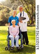 healthcare workers outdoors with disabled senior patient