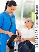 medical doctor checking senior patient's blood pressure