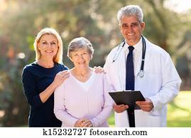 medical doctor standing with senior patient and her daughter