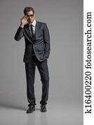 Men in full suit. Full length of confident young businessmen in sunglasses standing isolated on grey