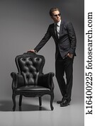 Men with chair. Full length of confident young businessmen in sunglasses standing near the vintage chair while isolated on grey