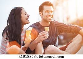 romantic couple eating ice cream at park