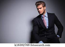 seated young fashion model in suit looks away