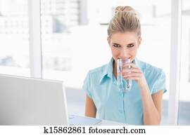 Smiling well dressed businesswoman drinking water