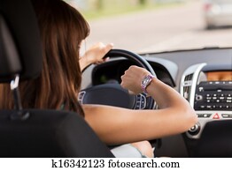 woman driving a car and looking at watch woman driving a car and looking at watch