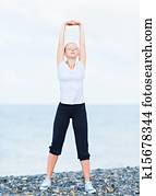 woman in white doing yoga and sport exercises on  beach