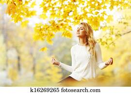 Woman meditating in autumn park