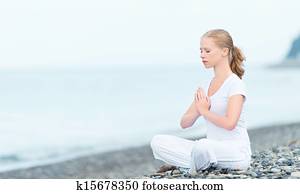 woman meditating in  lotus yoga on beach