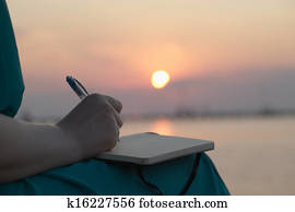 Woman writing in her diary at sunset