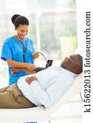 young african doctor checking senior patient's blood pressure