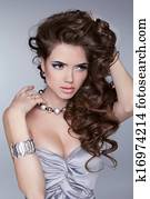 Beauty Portrait. Wavy Hairstyle.  Sexy girl with jewelry accessories isolated on grey background