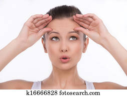 Forehead wrinkles. Surprised young woman touching her forehead and looking up while isolated on white