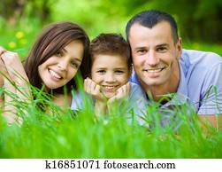 Happy family of three lying on grass