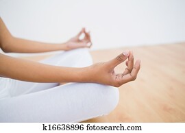Mid section of slim young woman meditating sitting in lotus position in fitness hall