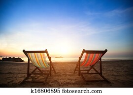 Pair of beach loungers on the deserted coast sea at sunrise, perfect vacation concept. Pair of beach loungers on the deserted coast sea at sunrise, perfect vacation concept.