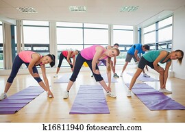 People stretching hands at yoga class in fitness studio