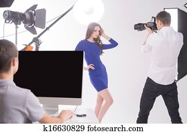Photographer and model at studio. Young man photographing model at studio