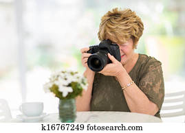 senior woman photographing flowers