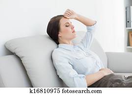 Serious well dressed woman sitting on sofa