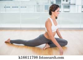Sporty gleeful brunette stretching on the floor