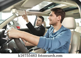 This model comes with added features. Handsome young salesman showing all the car features to the customer