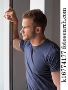 Thoughtful men. Handsome young man looking through the window