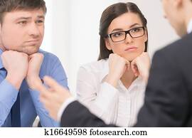 Two people listening to man. Woman with attention and man with bored face. Two people listening to man. Woman with attention and man with bored face.