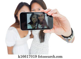 Two smiling asian sisters taking a self portrait