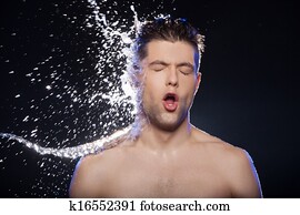 Water on face. Portrait of young wet men and the water splashing on his face