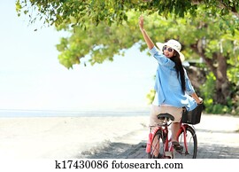 woman having fun riding bicycle at the beach